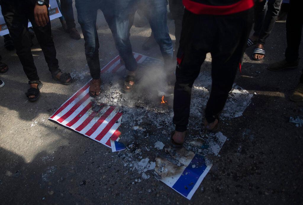 Palestinian protesters step over burning mocks of Israeli and American flags