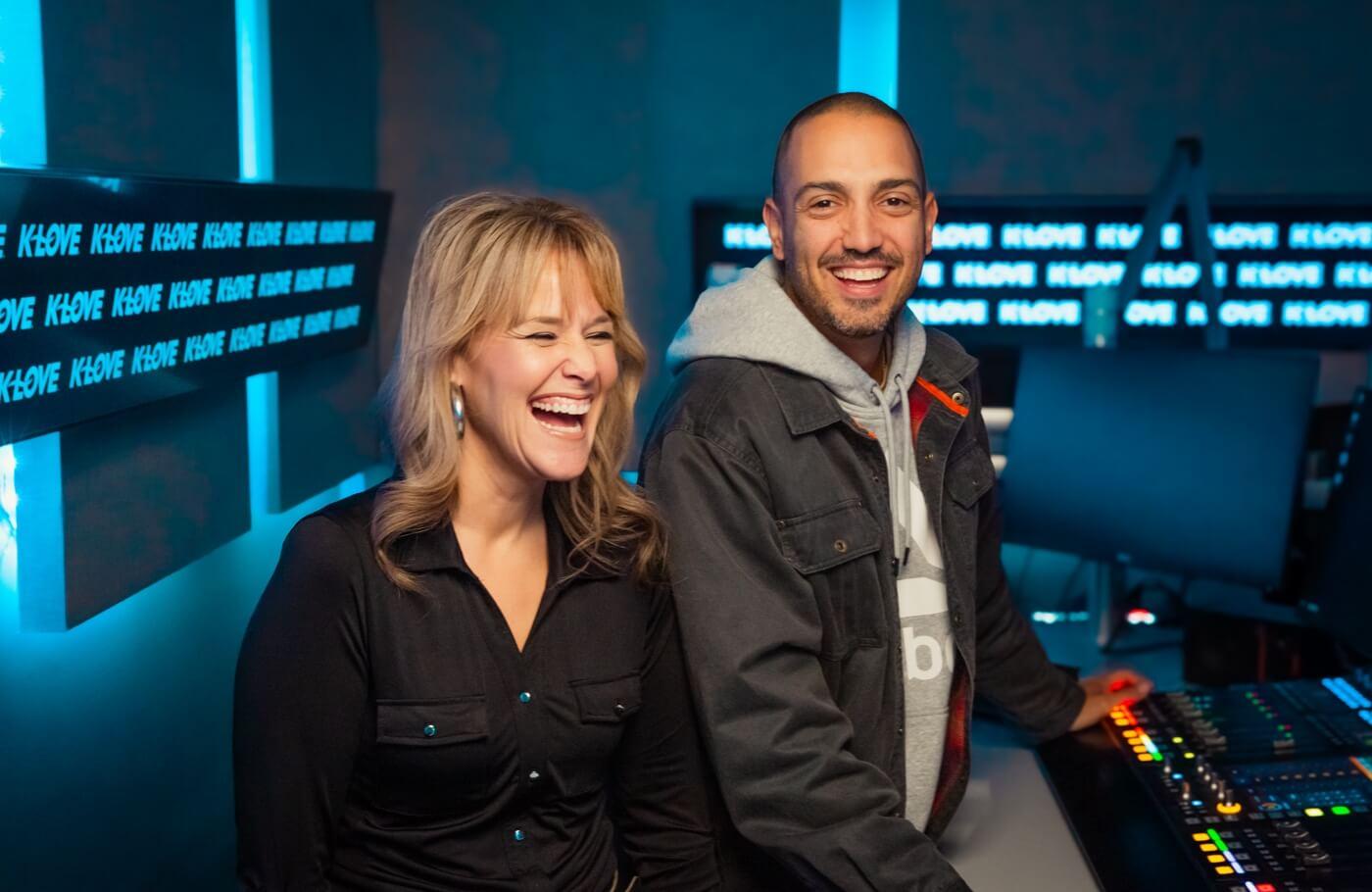 Carlos and Amy laughing and smiling together with a city scape behind them