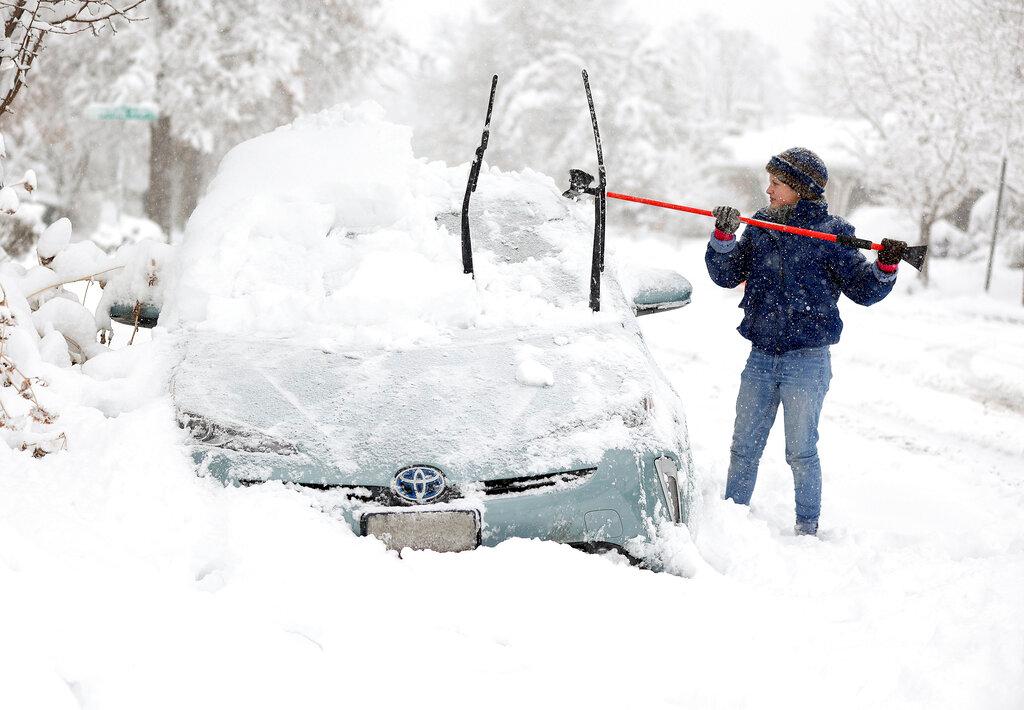 Cathy Morgan-Mace cleans snow and ice off her family's car during a snowstorm in Salt Lake City, Utah