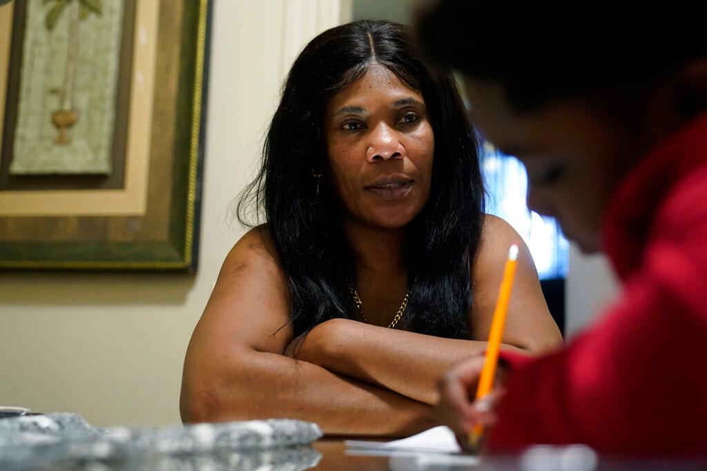 Evena Joseph, left, sits with her son J. Ryan Mathurin, 9, as he does his homework, at their home, in Boston.