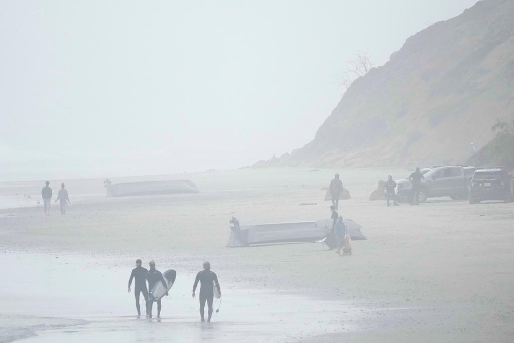 Two boats, one overturned, sit on Blacks Beach, Sunday, March 12, 2023, in San Diego.