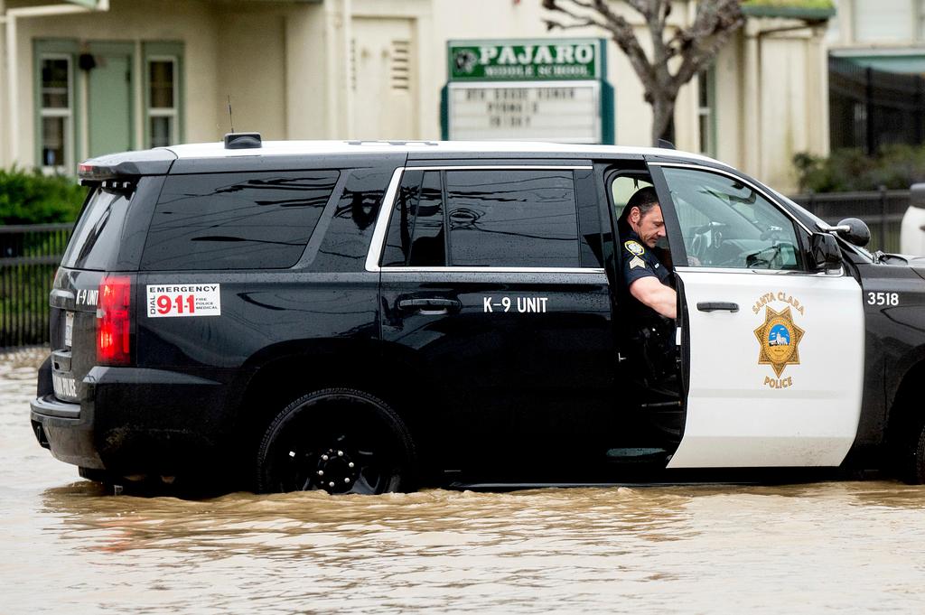 A sheriff's deputy checks floodwater levels while driving through the community of Pajaro in Monterey County, Calif.