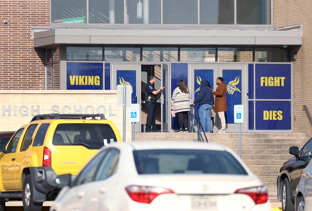 An Arlington police officer speaks to individuals outside of Lamar High School in Arlington during a lockdown after a shooting on Monday, March 20, 2023. 