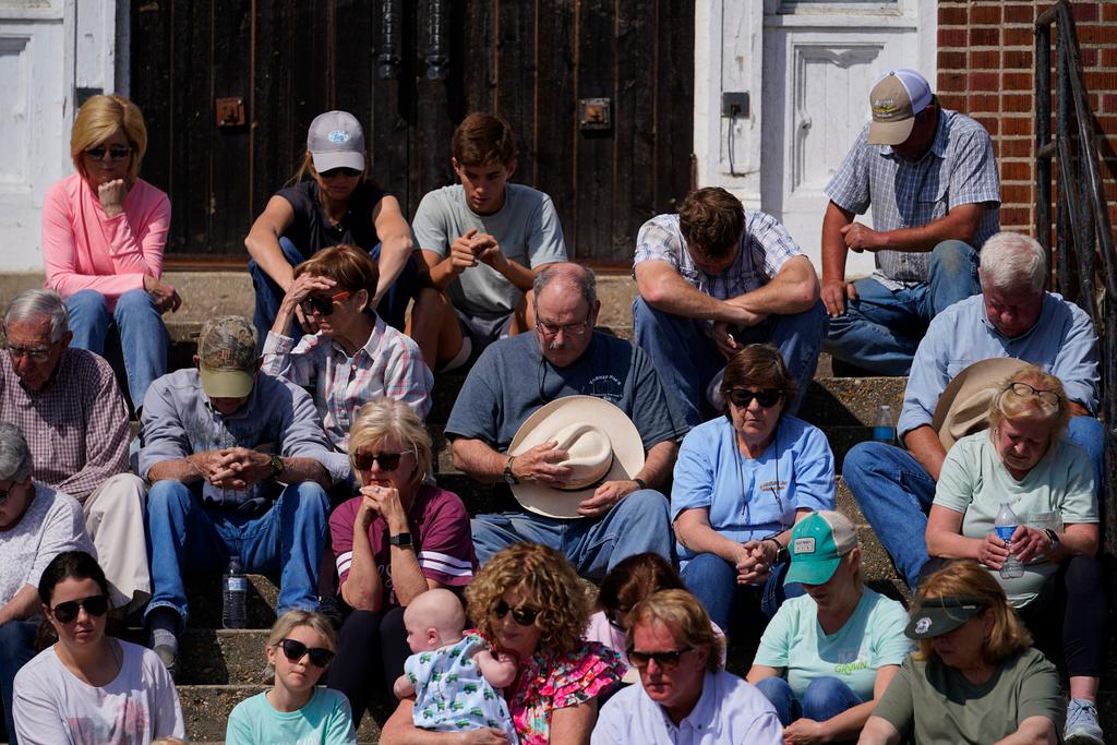 People sit and pray on the steps of the Rolling Fork United Methodist Church while worshiping