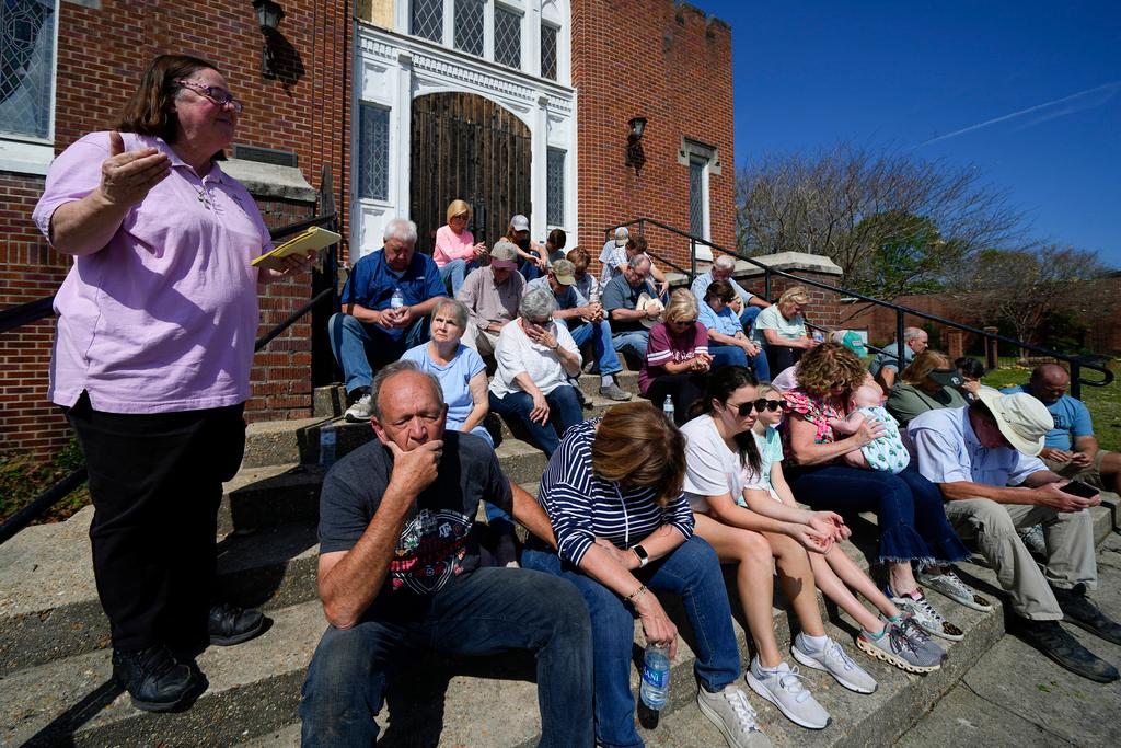 Rev. Mary Stewart, left, of Rolling Fork United Methodist Church, leads a prayer as people worship on the steps of the church