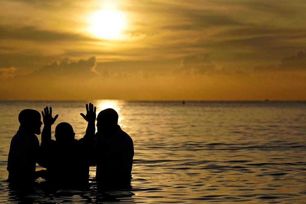 Louis "Jerry" Barrios, second from left, reacts after being baptized by Co-Pastors Rev. Brian Glasford, right, and his brother Rev. Jason Glasford, left, in the Atlantic Ocean during an Easter sunrise service with the New Life Missionary Baptist Church, Sunday in Miami Beach