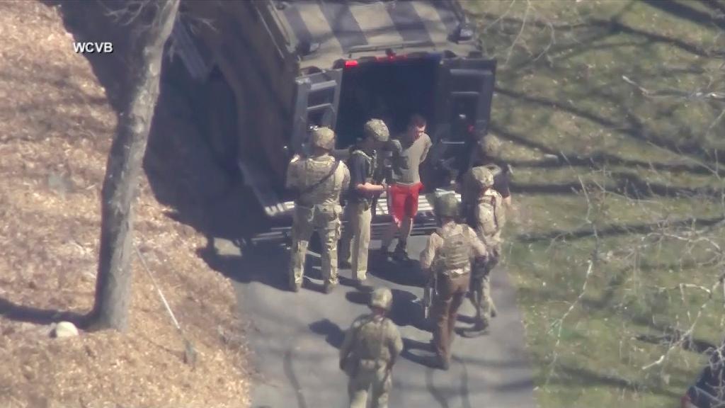 Suspect  Jack Teixeira, in T-shirt and shorts, being taken into custody by armed tactical agents 