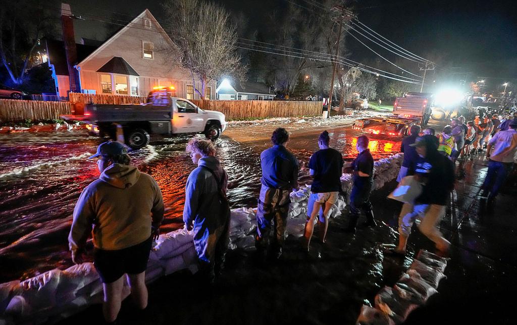 People work to protect homes into the night along 1700 South in Salt Lake City from the rising flow of Emigration Creek through Wasatch Hollow Park