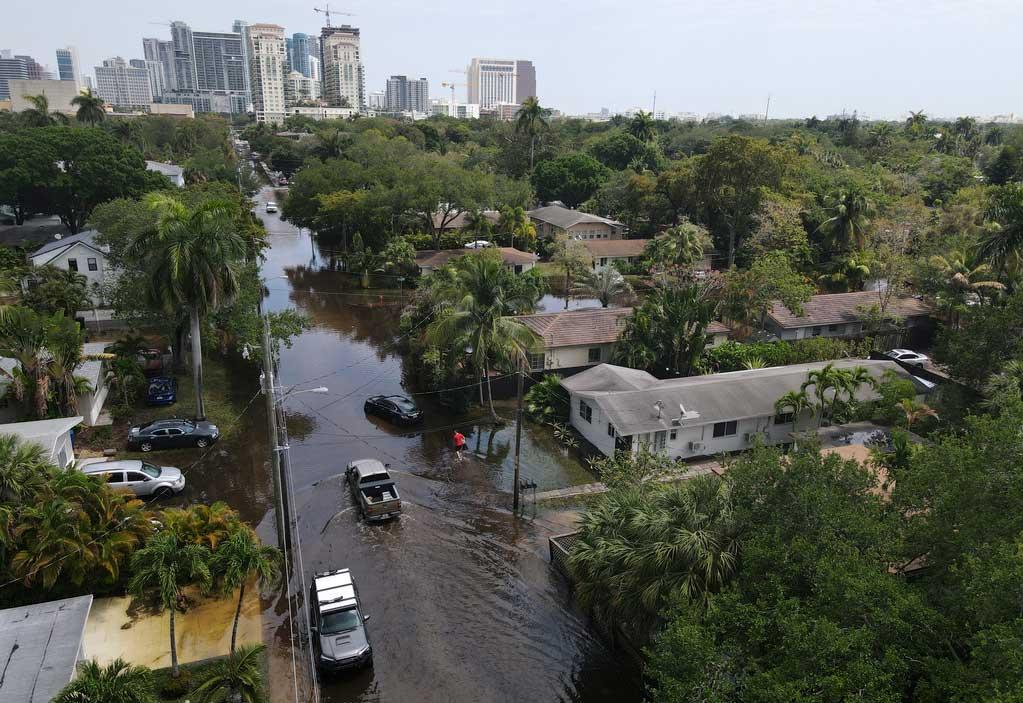 Trucks and a resident on foot make their way through receding floodwaters in the Sailboat Bend neighborhood of Fort Lauderdale, Fla.