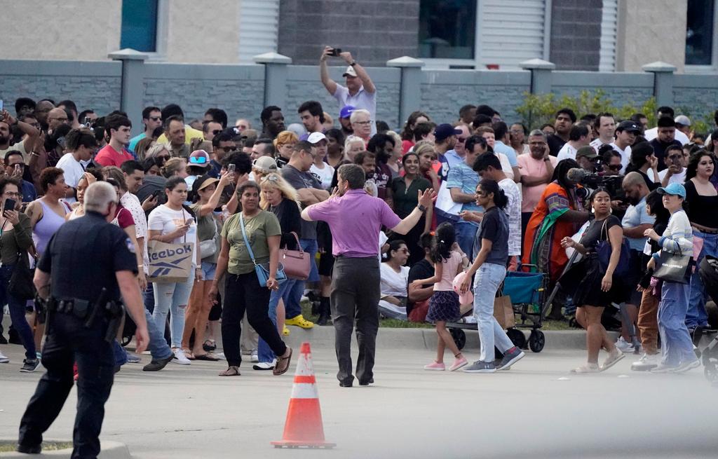 People gather across the street from a shopping center 