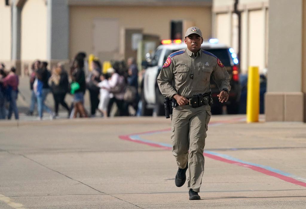 A law enforcement officer runs as people are evacuated from a shopping center where a shooting occurred Saturday, May 6, 2023, in Allen, Texas.