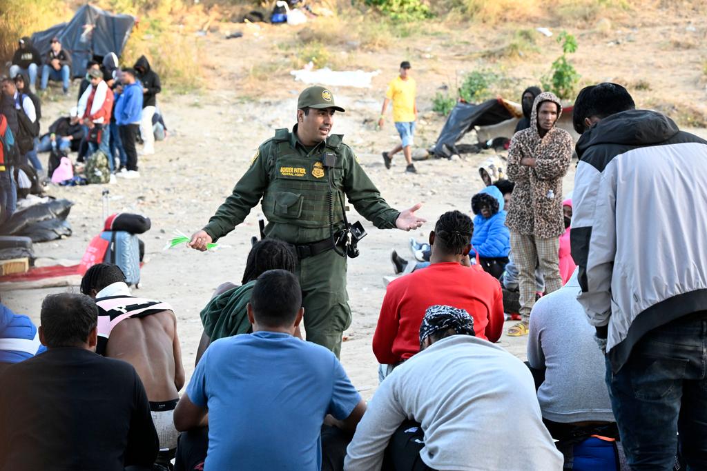 U.S. Border Patrol agent talks with asylum-seekers waiting between the double fence along the U.S.-Mexico border near Tijuana