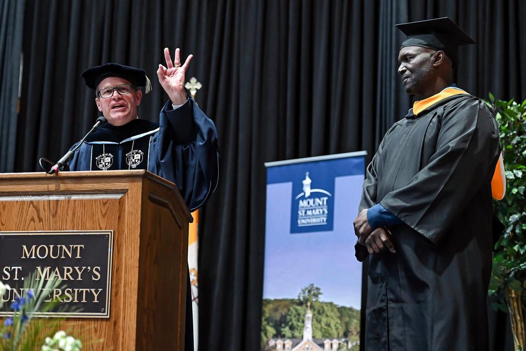 Timothy Trainor, left, President of Mount St Mary's University shows three fingers for the amount of Super Bowl rings that Tampa Bay Buccaneers head coach Todd Bowles, right, has as he introduces Bowles at the 215th commencement exercise for Mount St Mary's University, Saturday, May 13, 2023