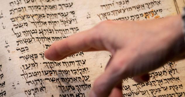 Man's finger pointing to Hebrew text on ancient Bible