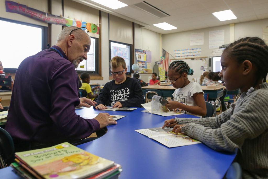 Richard Evans, a teacher at Hyde Park Elementary School, helps Shaundrea Baines, right, during a reading circle in class in Niagara Falls, N.Y.