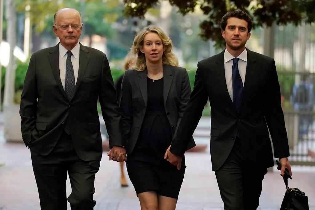 Former Theranos CEO Elizabeth Holmes, center, arrives at federal court with her father, Christian Holmes IV, left, and partner, Billy Evans, in San Jose, Calif., Monday, Oct. 17, 2022. As Elizabeth Holmes prepares to report to prison next week, the criminal case that laid bare the blood-testing scam at the heart of her Theranos startup is entering its final phase.