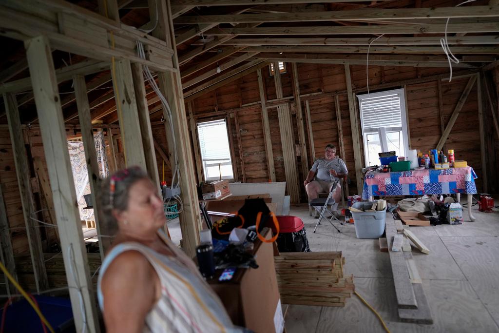 Jacquelyn and Timothy Velazquez sit inside the gutted shell of their 910 square foot two-bedroom home, which was damaged when Hurricane Ian's storm surge rose to within inches of the ceiling, in Fort Myers Beach, Fla.