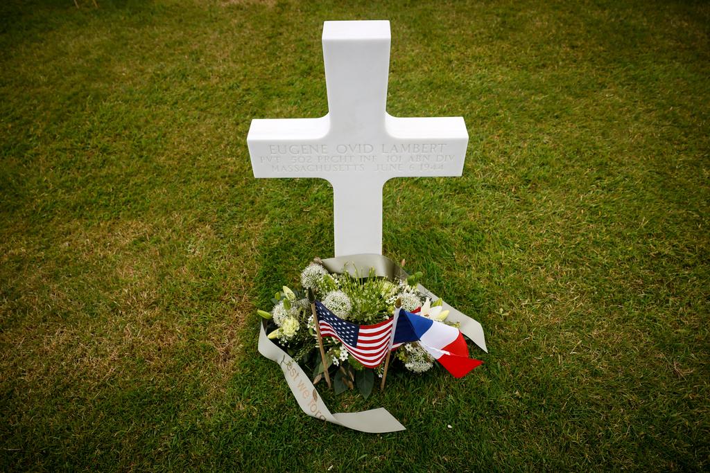 An American flag, left, and French flag lay at headstones in the American Cemetery in Colleville-sur-Mer, Normandy