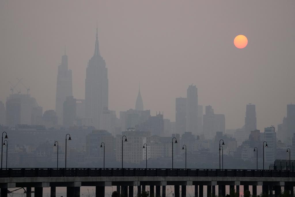 The sun rises over a hazy New York City skyline as seen from Jersey City, N.J.