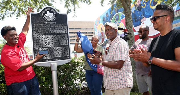 A group of men and women around a sign for Juneteenth