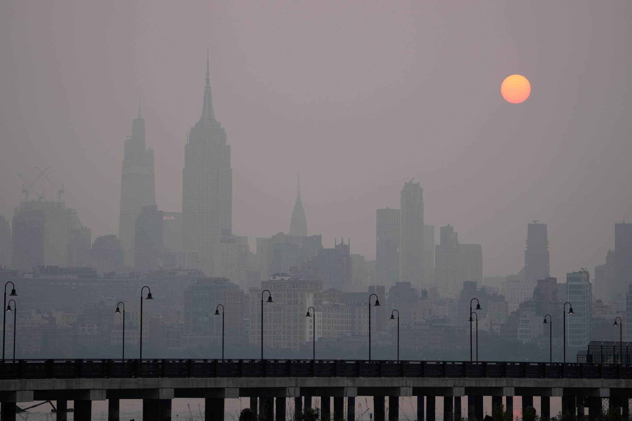 The sun rises over a hazy New York City skyline as seen from Jersey City, N.J., Wednesday, June 7, 2023. 