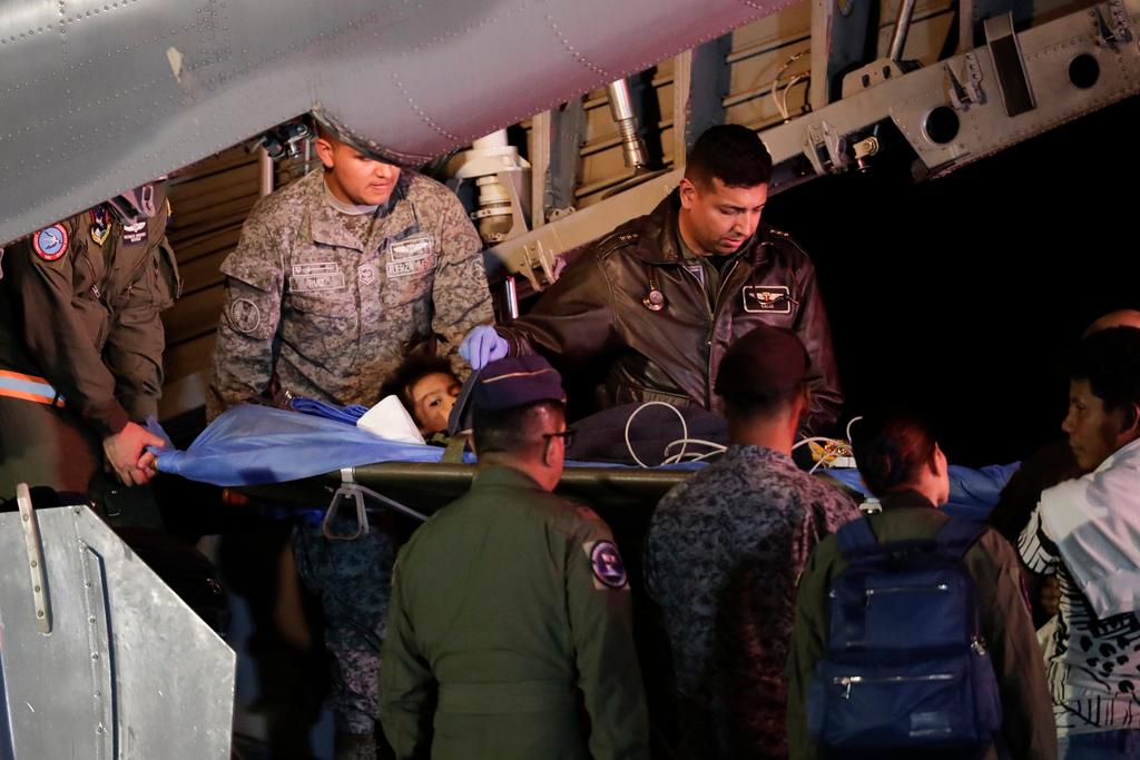 Military personnel unload from a plane one of four children who were found