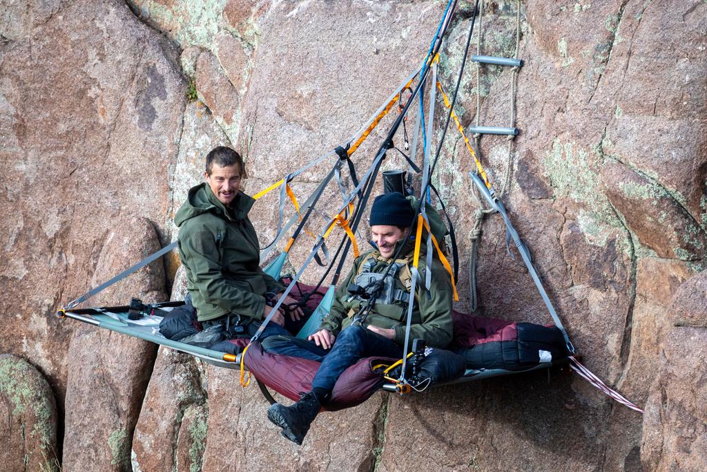 Bradley Cooper, left, and Bear Grylls on a paraledge hung off the edge of Pathfinder Canyon in Wyoming, in a scene from “Running Wild with Bear Grylls: The Challenge"