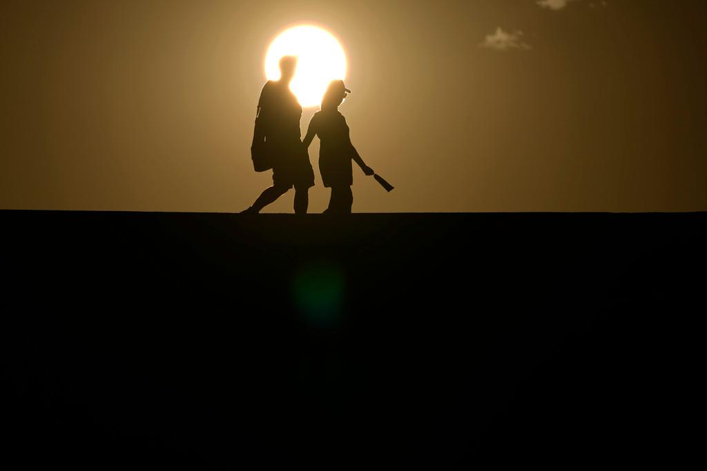 People walk along a trail as the sun sets in Death Valley National Park, Calif.