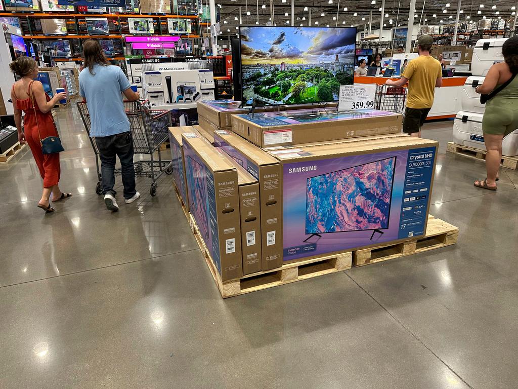 Shoppers glide past a display of big-screen televisions in a Costco warehouse