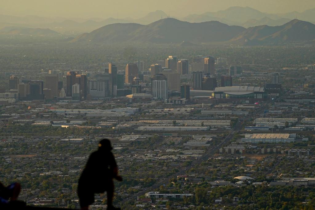 Man overlooks downtown Phoenix at sunset atop South Mountain