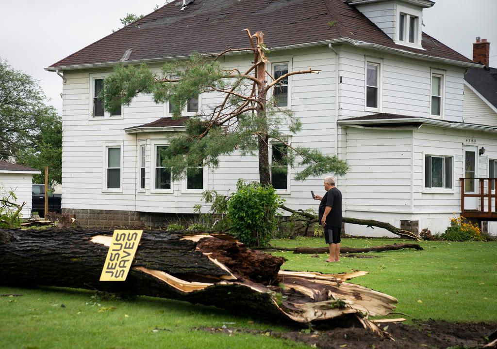 Tony Bielksi, of South Rockwood takes some photos of a neighbors fallen tree on South Huron River Drive on Friday, Aug. 25, 2023