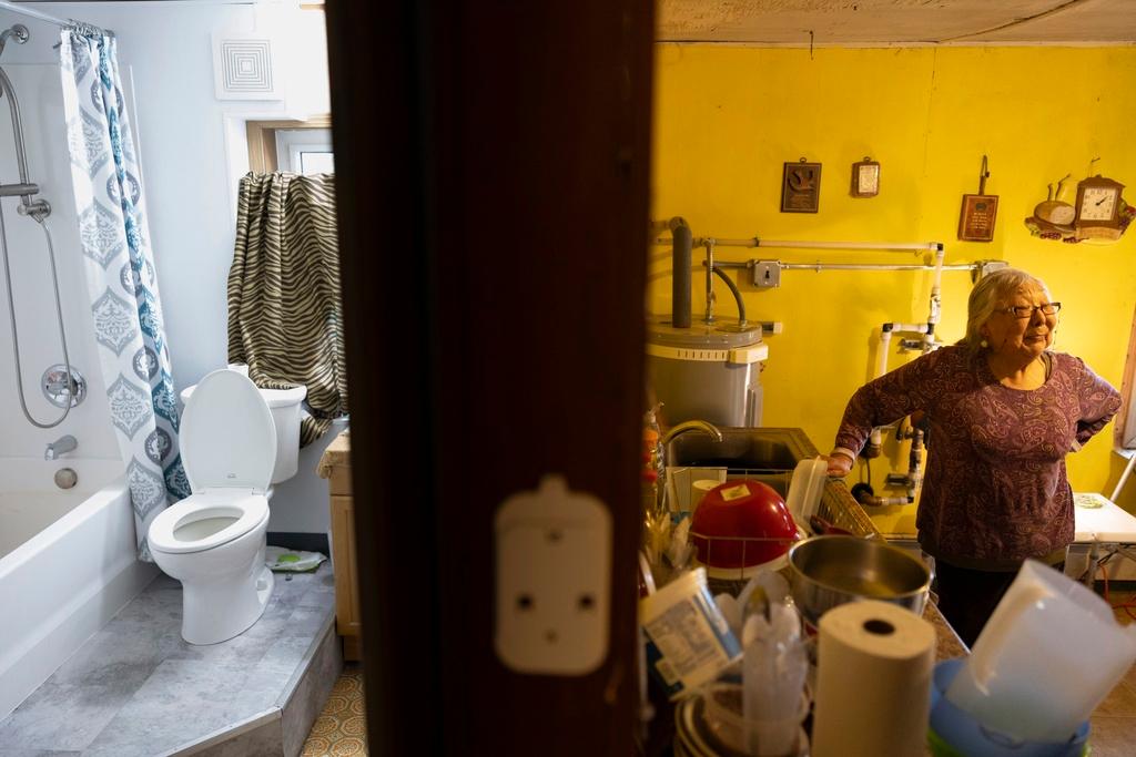 Mary Lou Beaver stands beside her family's kitchen sink in Akiachak, Alaska. "It's fabulous. I'm glad they don't have to carry honey buckets," Beaver said. Originally born in Akiachak, the retired teacher now lives in Anchorage. She recalled packing water from the river in her youth, collecting rainwater and using an outhouse.