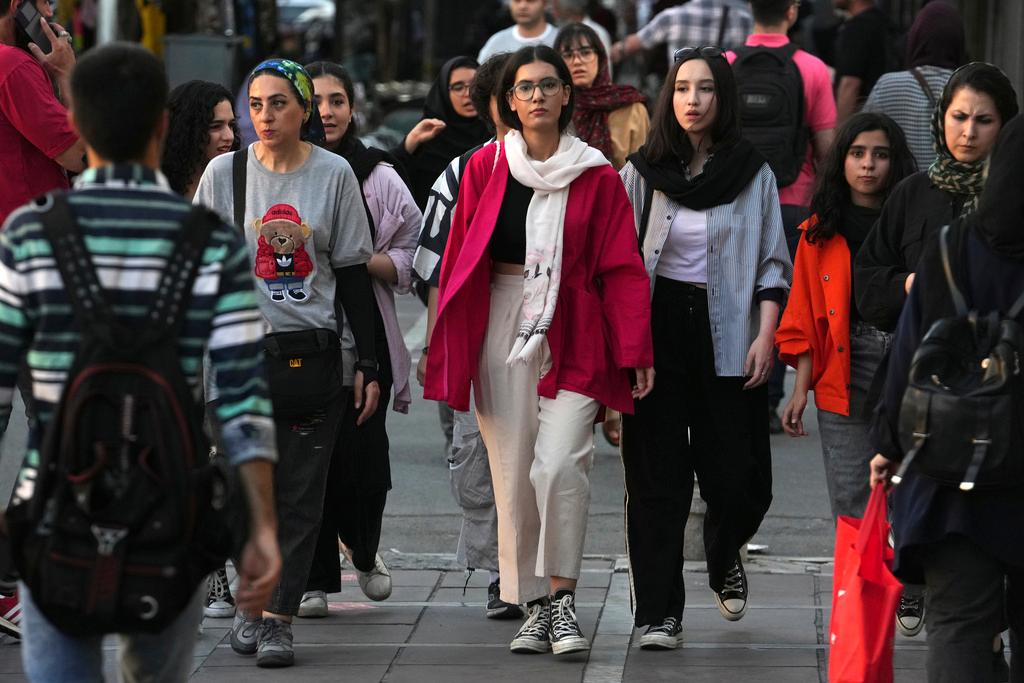 Iranian women, some without wearing their mandatory Islamic headscarves, walk in downtown Tehran, Iran