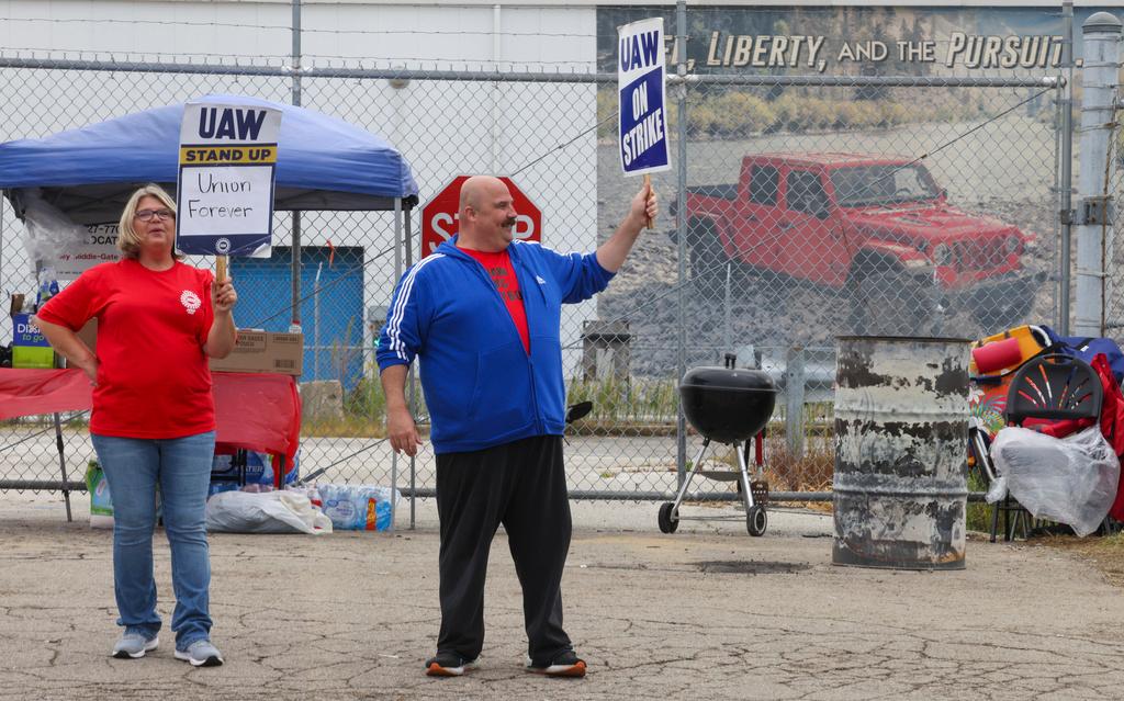 United Auto Workers union members and Jeep workers Sheri Fisher and Mark Zydel hold up signs to traffic during a strike for improved compensation outside of the Stellantis Toledo Assembly Complex on Thursday, Sept. 28, 2023 in Toledo, Ohio.