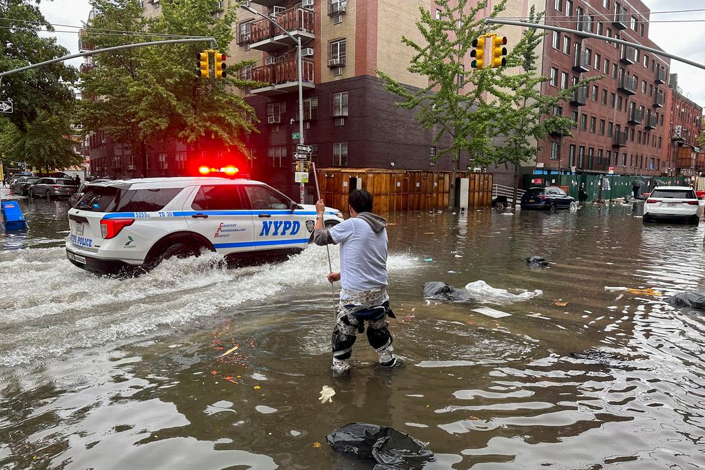 A man works to clear a drain in flood waters