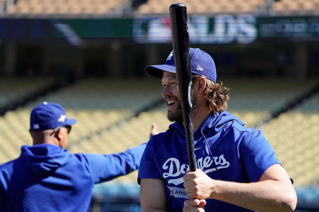 Los Angeles Dodgers starting pitcher Clayton Kershaw, right, warms up as manager Dave Roberts stands in the background during practice 