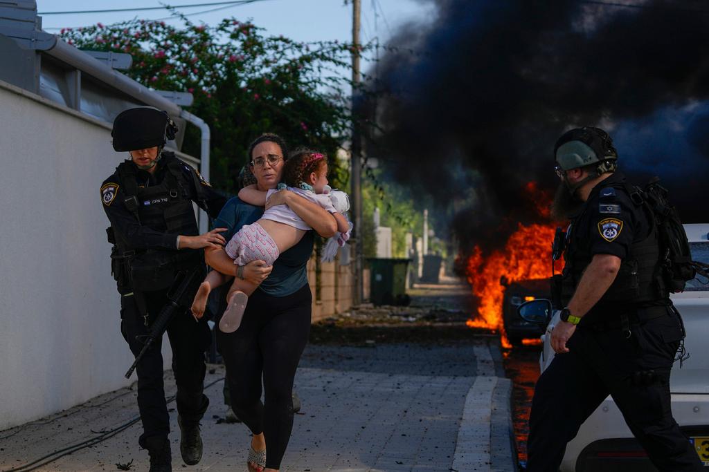 Police officers evacuate a woman and a child from a site hit by a rocket fired from the Gaza Strip, in Ashkelon, southern Israel