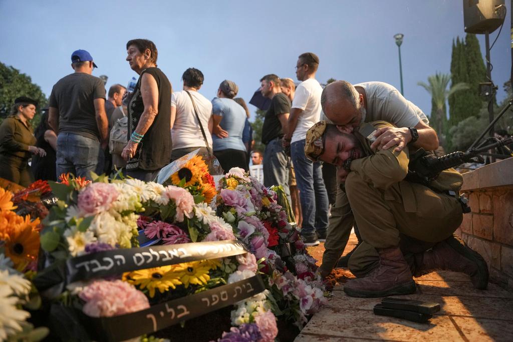 Friends and relatives of Ilai Bar Sade mourn next to his grave during his funeral at the military cemetery in Tel Aviv