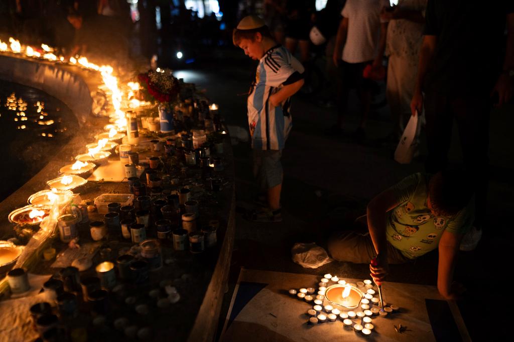 A boy lights candles in the form of the Star of David in honour of victims of the Hamas attacks during a vigil at the Dizengoff square in central Tel Aviv