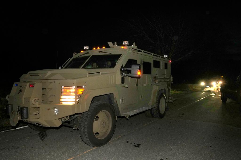 Law enforcement officers depart a scene in an armored vehicle