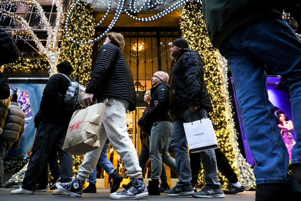 Shoppers carry shopping bags down Fifth Avenue, Monday, Dec. 19, 2022, in New York. 