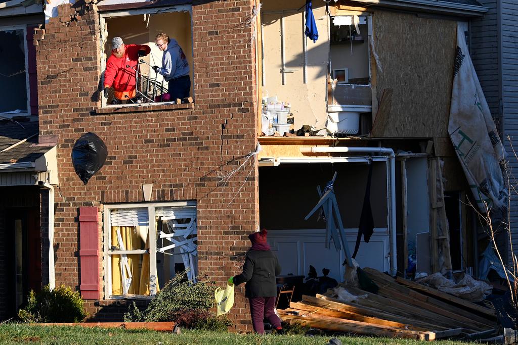 Donna Rogers, bottom right, watches while friends toss bags of clothes from the second floor of her son's damaged home in the West Creek Farms neighborhood 