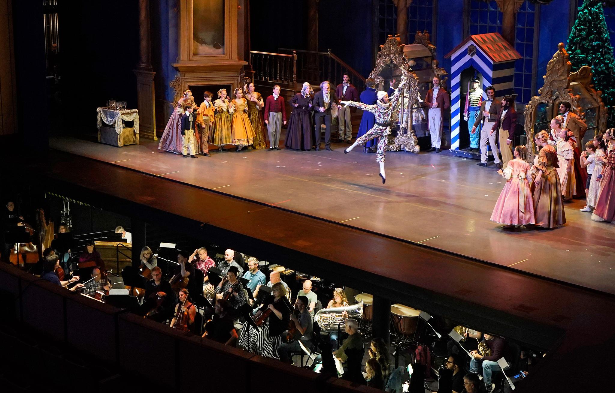 Ballet dancers on stage with a clear view of the orchestra playing instruments in the pit.