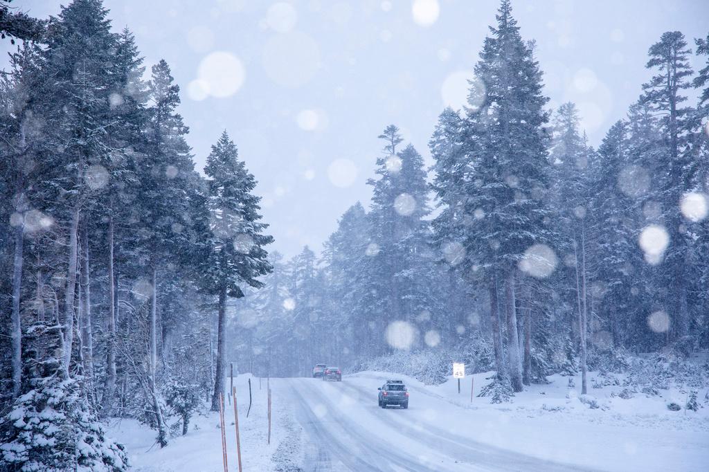 Cars make their way through the snow in Mammoth Lakes, Calif.