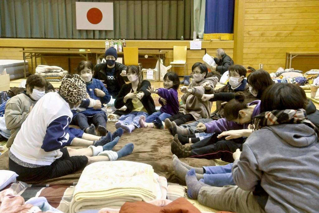 Local residents in the quake-hit area, stretch out together at a shelter in Anamizu, Ishikawa prefecture, Sunday, Jan. 7, 2024.