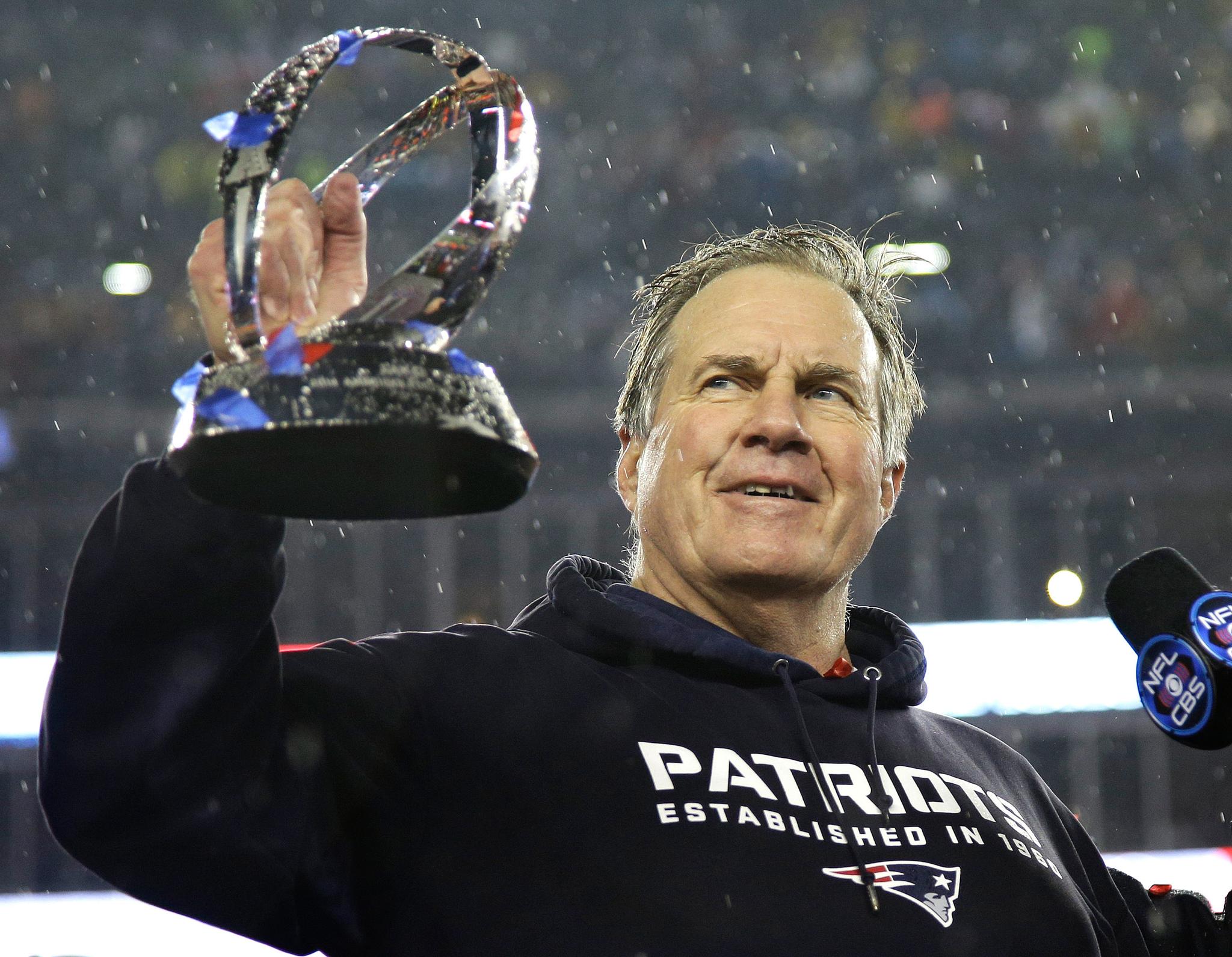 Football coach holding up a football trophy