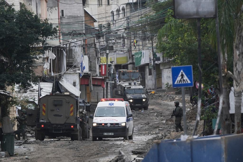 Ambulance passes by Israeli troops duringarmy raid in the Tulkarem refugee camp, West Bank, Israel