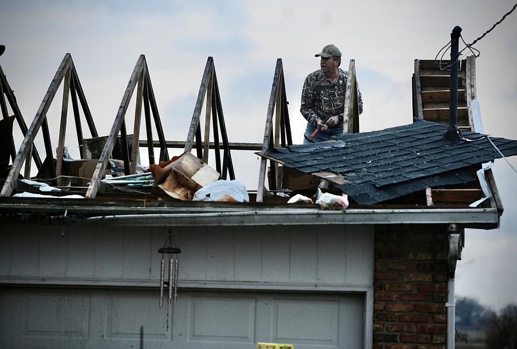 Ted Williams works to put a temporary cover on the roof of his in-laws home following a severe storm near Springfield, Ohio