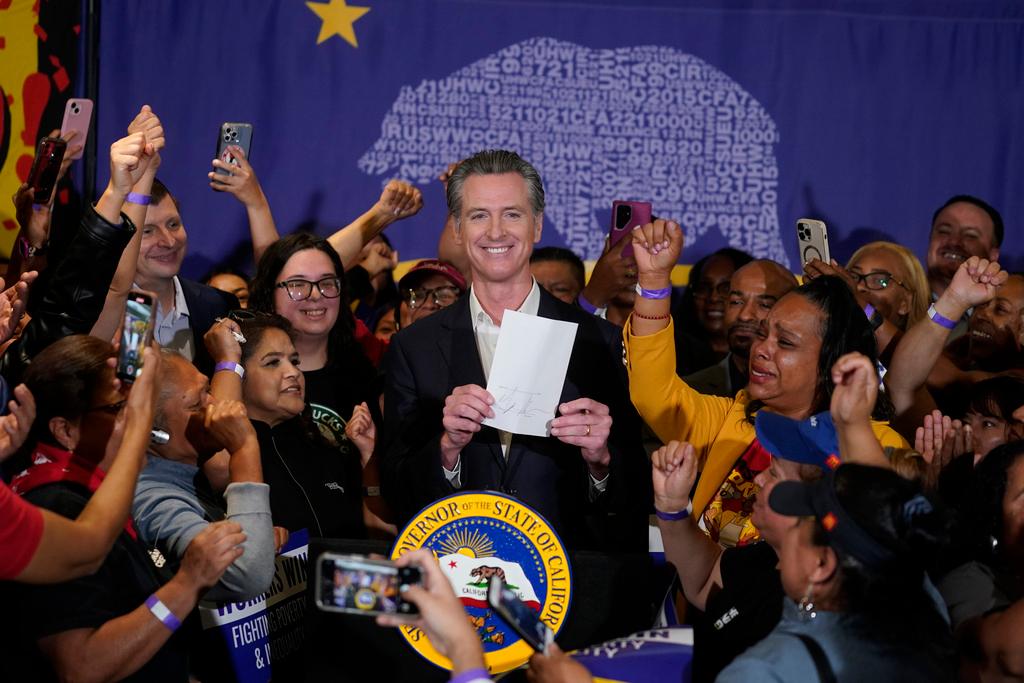 California Gov. Gavin Newsom signs the fast food bill surrounded by fast food workers at the SEIU Local 721 in Los Angeles