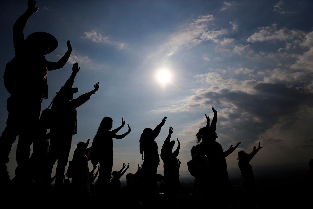 Visitors hold their hands out to receive the sun's energy as they celebrate the Spring equinox atop the Pyramid of the Sun in Teotihuacan, Mexico, Thursday, March 21, 2019.